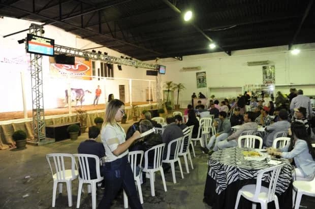Público sentado em mesas durante um leilão no tatersal